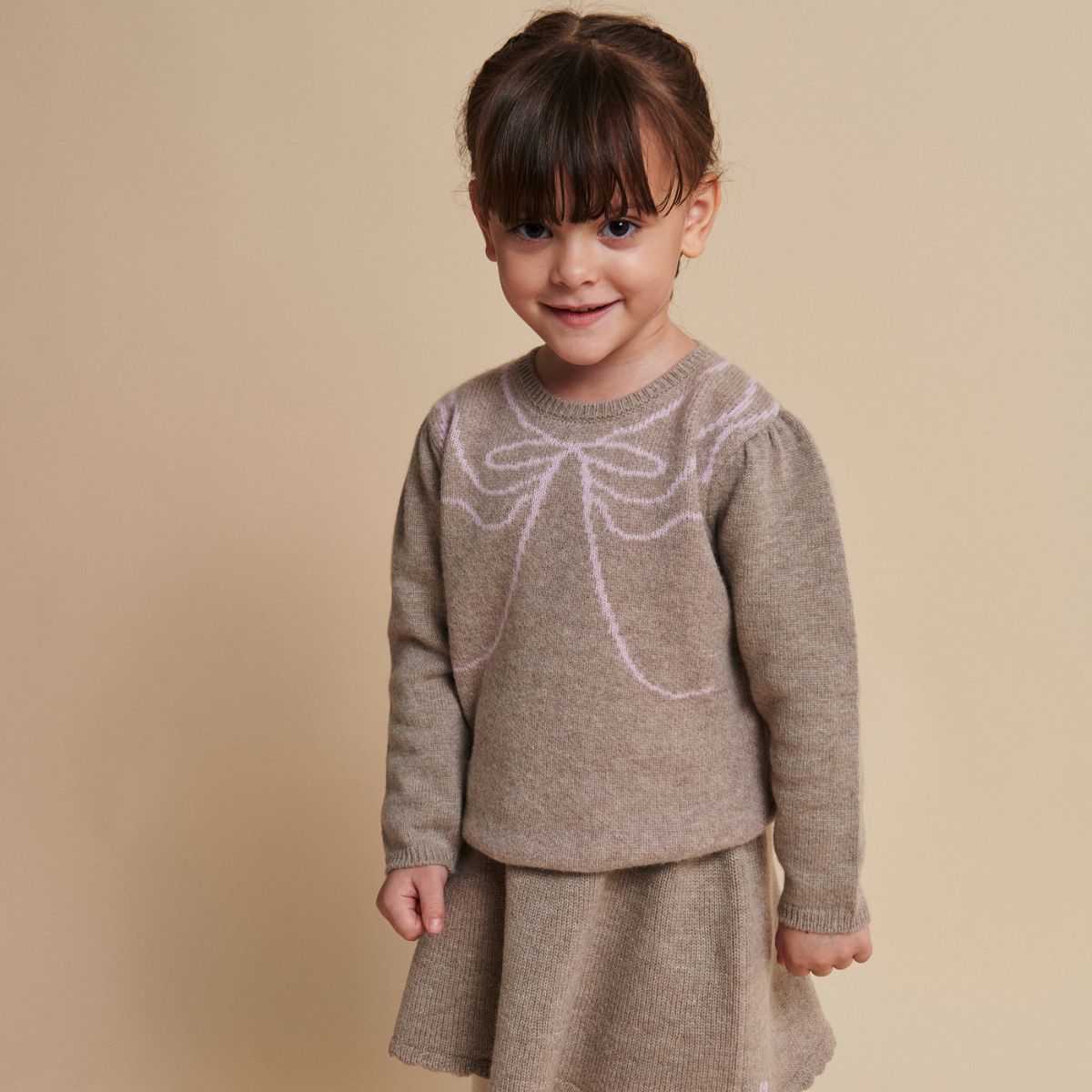 De Copenhagen Colors cashmere bow deco trui sand/bubblegum is een warme trui met een speels accent. De zachte beige kleur vormt een rustige basis, terwijl de roze strik op de borst de trui opvallend maakt. VanZus