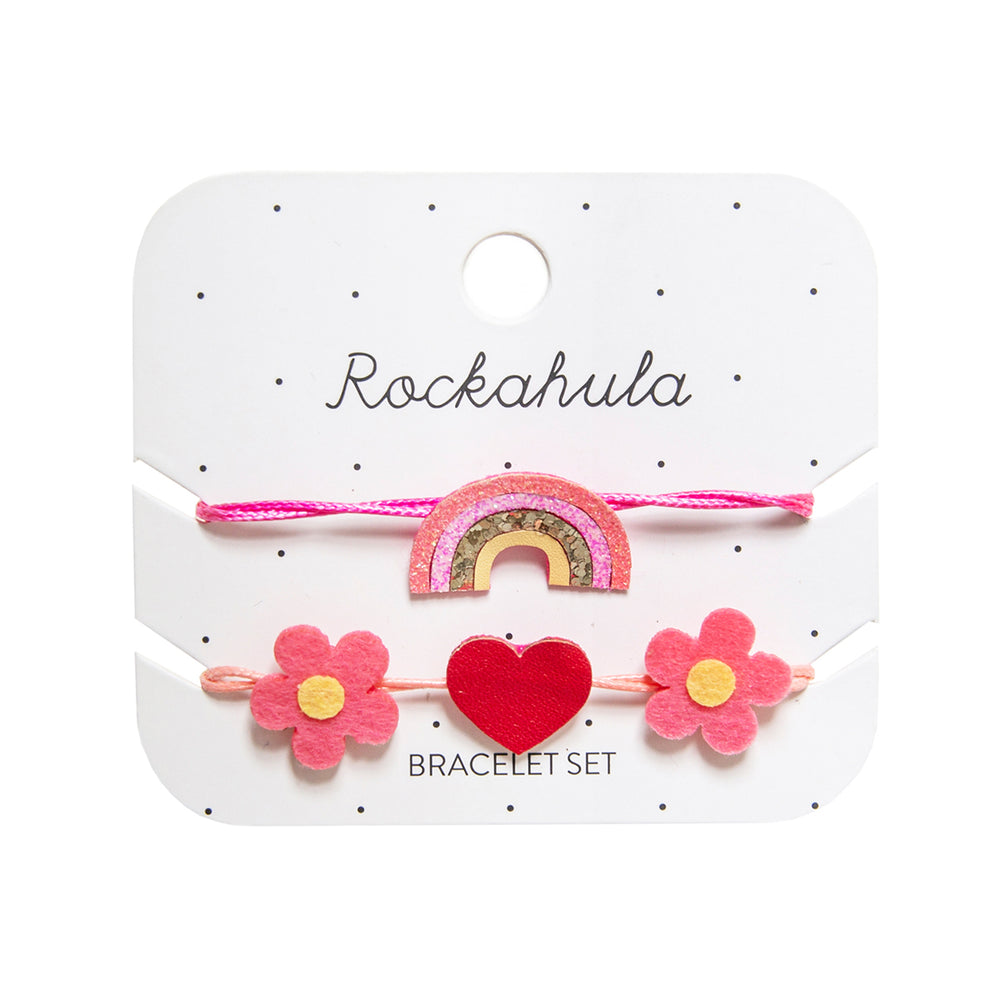 Armcandy voor jouw mini: Rockahula’s hippy rainbow armbandjes set. Een armbandje met regenboog in de kleuren roze, geel en goud en een armbandje met roze bloemen en nepleren rode hart. Eenvoudig verstelbaar. VanZus