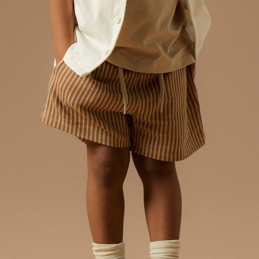 Creëer een relaxte en hippe look met deze haris regular short in de kleur irish cream van het merk Name It! Deze short is gemaakt van katoen en zit dan ook heel comfortabel en voelt zacht aan. De short heeft een mooie bruine kleur met beige streepjes en heeft een subtiele textuur. VanZus