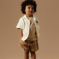 Creëer een relaxte en hippe look met deze haris regular short in de kleur irish cream van het merk Name It! Deze short is gemaakt van katoen en zit dan ook heel comfortabel en voelt zacht aan. De short heeft een mooie bruine kleur met beige streepjes en heeft een subtiele textuur. VanZus