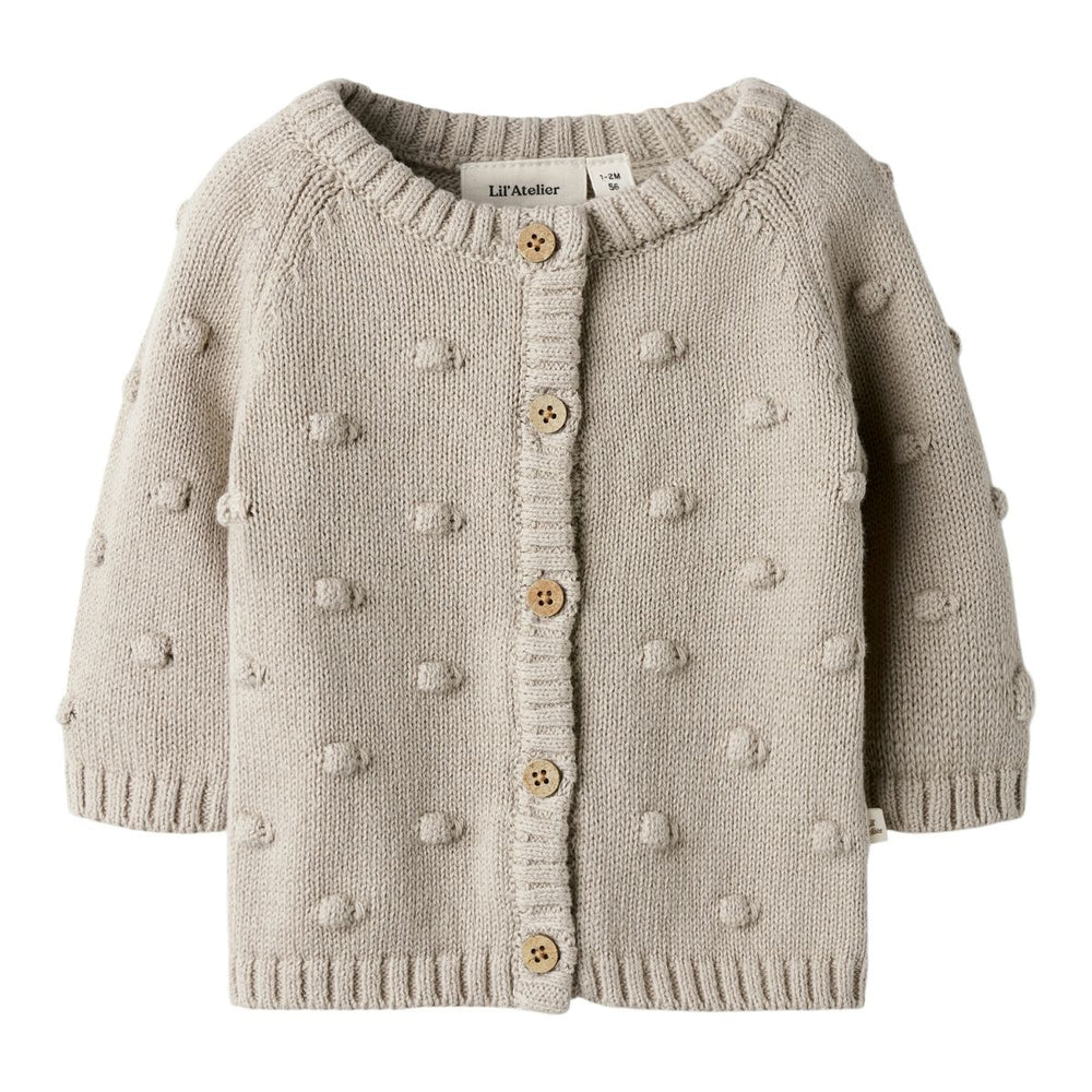 Het baby gable knit vestje in de kleur oxford tan van het merk Lil' Atelier is een must-have voor elke babygarderobe. Dit stijlvolle gebreide vestje, gemaakt van 80% biologisch katoen en 20% gerecycled katoen, biedt niet alleen comfort, maar ook een duurzame keuze.VanZus