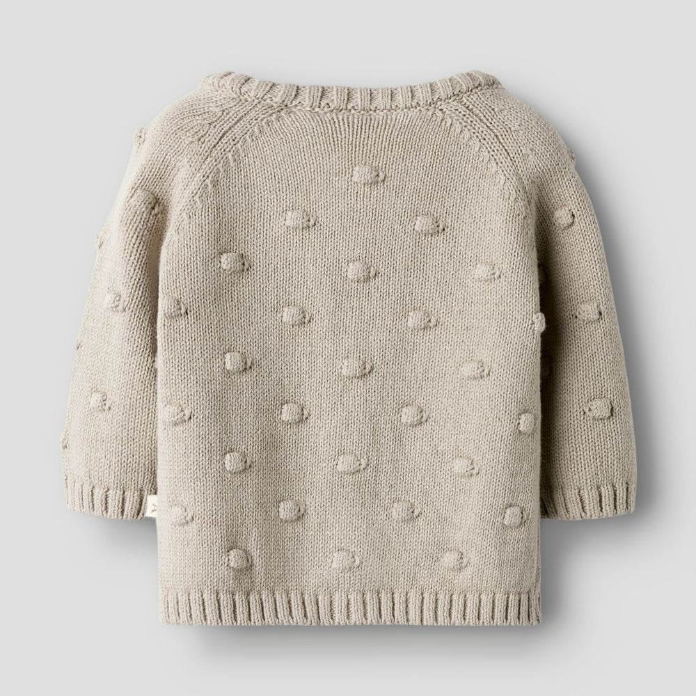 Het baby gable knit vestje in de kleur oxford tan van het merk Lil' Atelier is een must-have voor elke babygarderobe. Dit stijlvolle gebreide vestje, gemaakt van 80% biologisch katoen en 20% gerecycled katoen, biedt niet alleen comfort, maar ook een duurzame keuze.VanZus