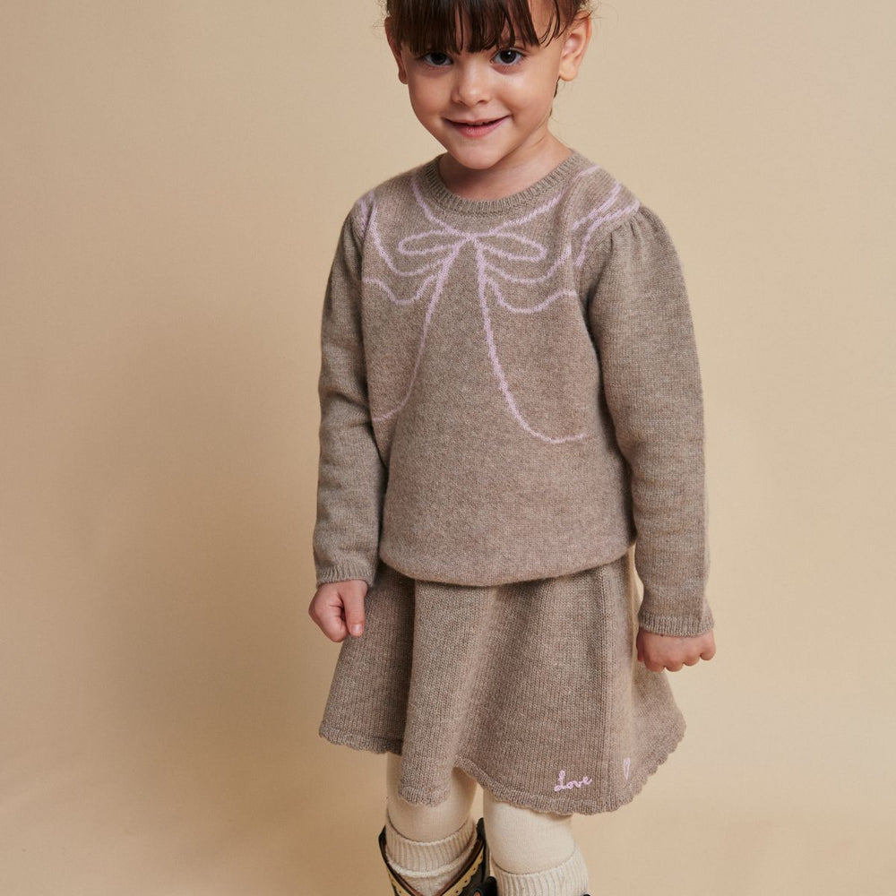 Het Copenhagen Colors cashmere rokje sand melange is een zacht en warm rokje voor de winter. De beige basiskleur wordt speels aangevuld met roze details: ‘love’ op de voorkant, een hartje achterop. VanZus