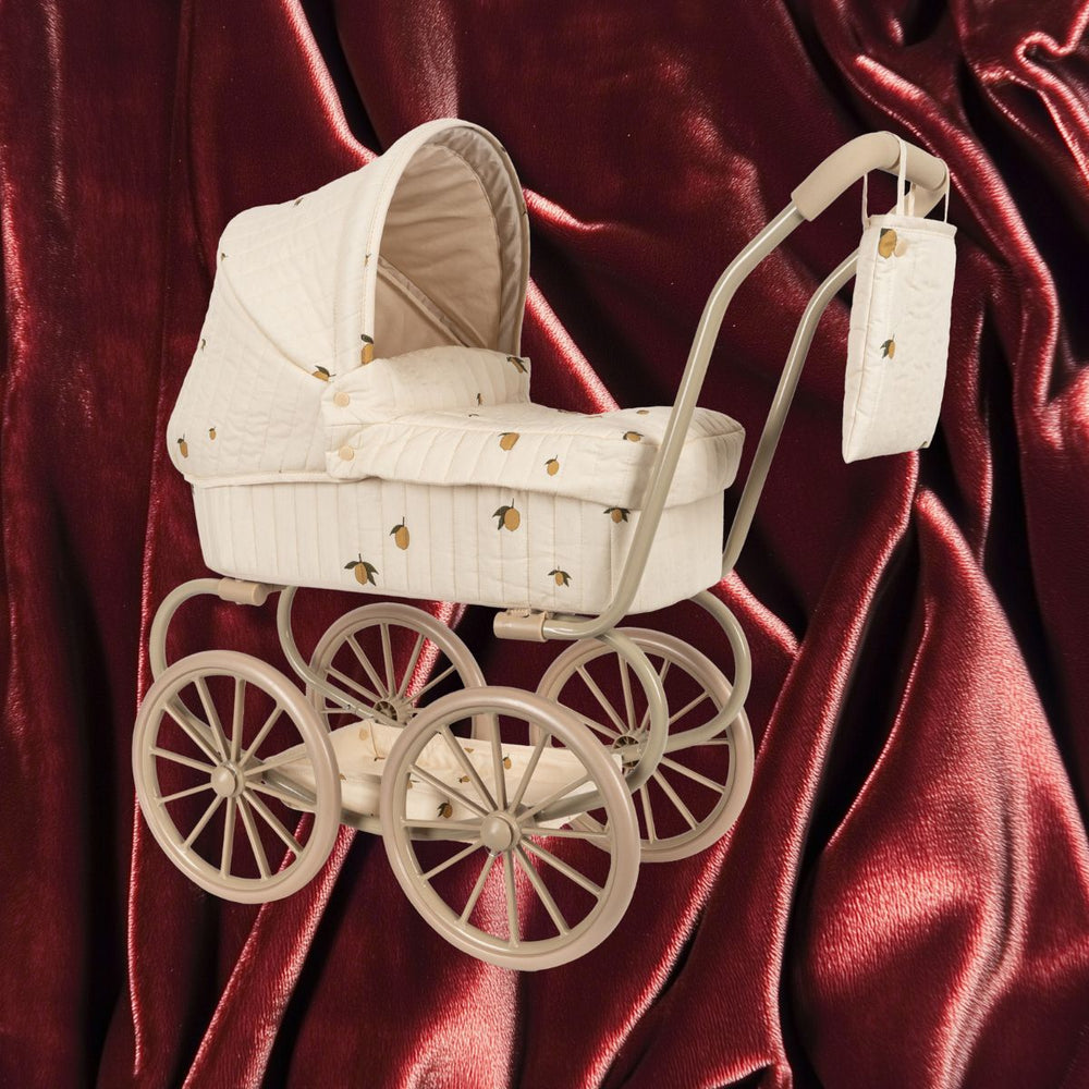 De Konges Slojd minnie poppenwagen in lemon is perfect voor kleine poppenouders. Met grote wielen, een zacht matrasje en een opbergmand biedt deze vintage-stijl wagen comfort en elegantie. VanZus