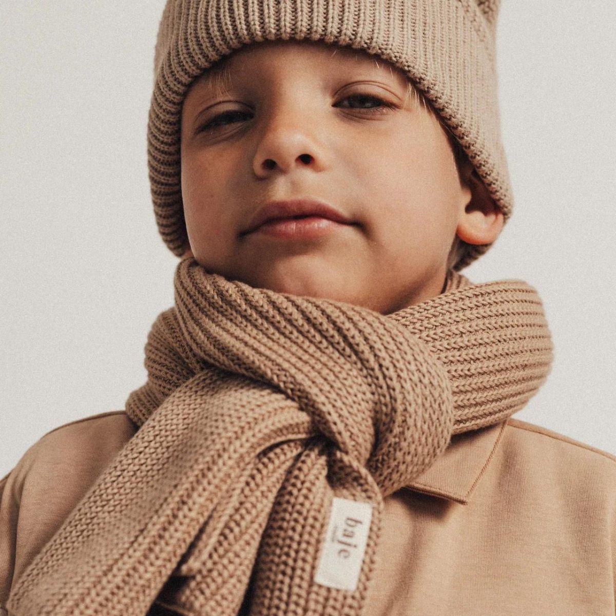 De Baje Studio riv sjaal en muts in de kleur taupe zijn de perfecte accessoires voor de winter. Met deze mooie set, bestaande uit een mooie muts en sjaal, blijft jouw kindje heerlijk warm. VanZus.