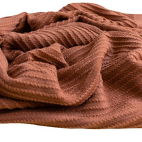 Deken akira van Hvid, in brick, biedt warmte en comfort voor je baby met zacht merino lamswol. Ribgebreid, zacht en warm. Een stijlvolle deken met harlekijn patroon. VanZus