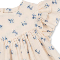 De coco jurk bow bleu van het Deense merk Konges Slojd is een betoverende keuze voor je kleintje. Deze schattige jurk in een neutrale witte kleur is gemaakt van ademende en lichte mousseline, perfect voor warme dagen. VanZus