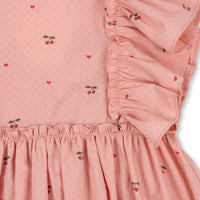 Hoe schattig is deze evia bow jurk in de variant cherry coeur van het merk Konges Slojd? Dit mooie jurkje met een roze kleur en een schattige kersenprint is het ideale jurk voor zowel feestelijke gelegenheden als alledaagse outfits. De jurk is gemaakt van 100% organisch katoen en heeft ruches bij de mouwen en een wijd uitlopende rok. VanZus