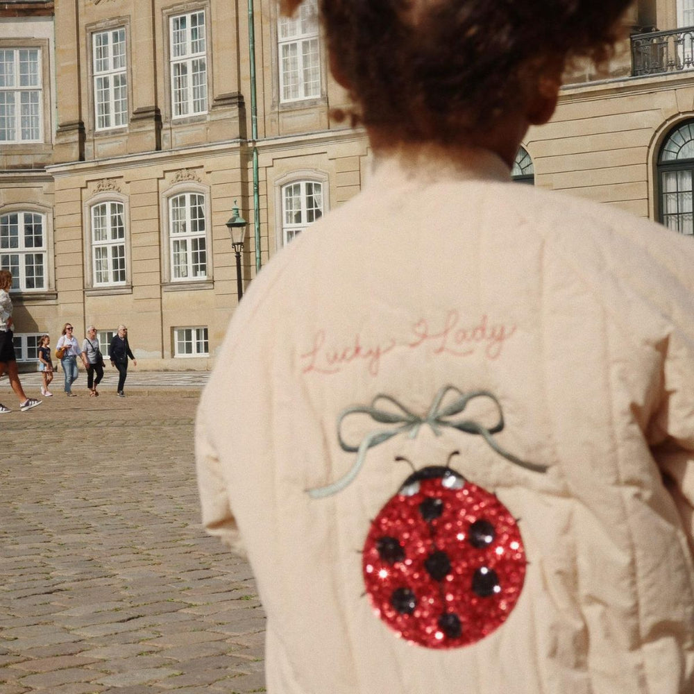 Je kindje steelt de show met dit stoere Konges Slojd juno sequin bomber jas in de variant frappé. Dit leuke zandkleurige bomberjack heeft een schattig lieveheersbeestje en de tekst 'lucky lady' op de achterkant neemt je mee terug naar je eigen kindertijd. VanZus