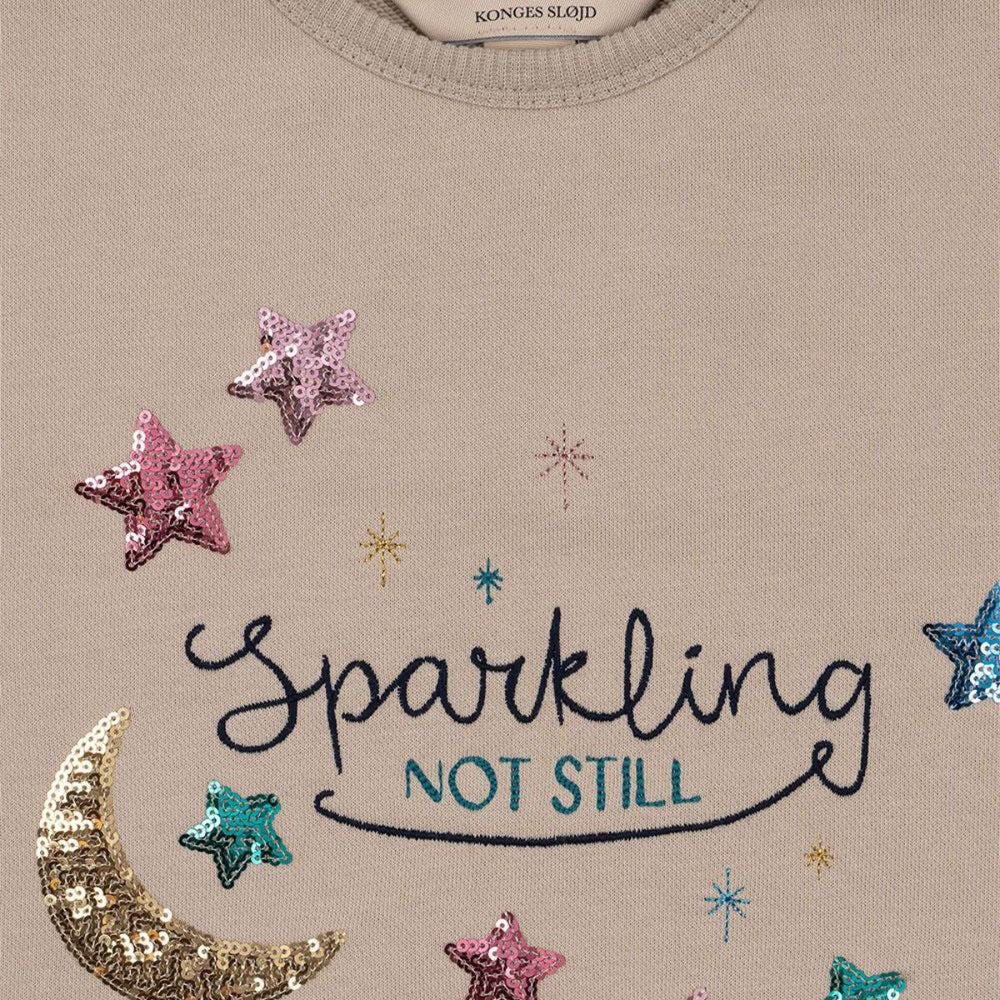 Het Konges Slojd lou sequin sweatshirt french oak is een must-have voor elke garderobe. Van zacht biologisch katoen, biedt het comfort en een trendy uitstraling met glitters, perfect voor school of casual uitjes! VanZus