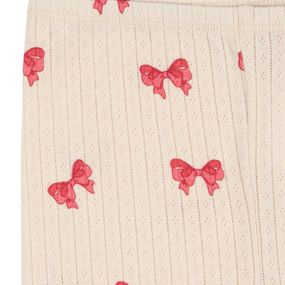 Wat een heerlijk, comfortabel broekje is dit. De minnie korte legging in de variant rosia bow van Konges Slojd heeft het model van een fietsbroekje of korte legging en heeft een witte kleur en een schattige roze print van strikjes. VanZus