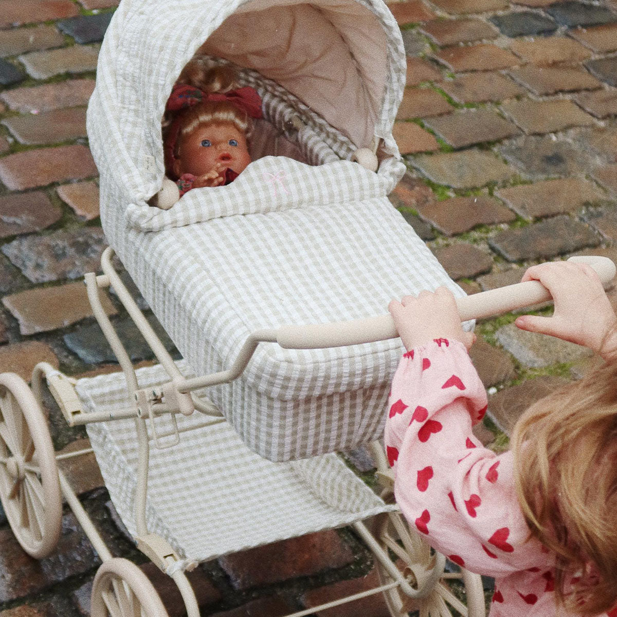 De Konges Slojd poppenwagen in tea check check heeft een vintage look en is ontworpen met vier grote wielen gemaakt van EVA materiaal voor extra stabiliteit. De kinderwagen voor poppen heeft een schattig ruitjespatroon. VanZus