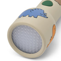 Deze leuke gry zaklamp in dinosaurs/mist van het merk Liewood is het ideale lampje om lekker knus nog even in het donker te kunnen lezen als je al in bed ligt, maar ook om spannende zoekspelletjes mee in het donker te spelen! VanZus