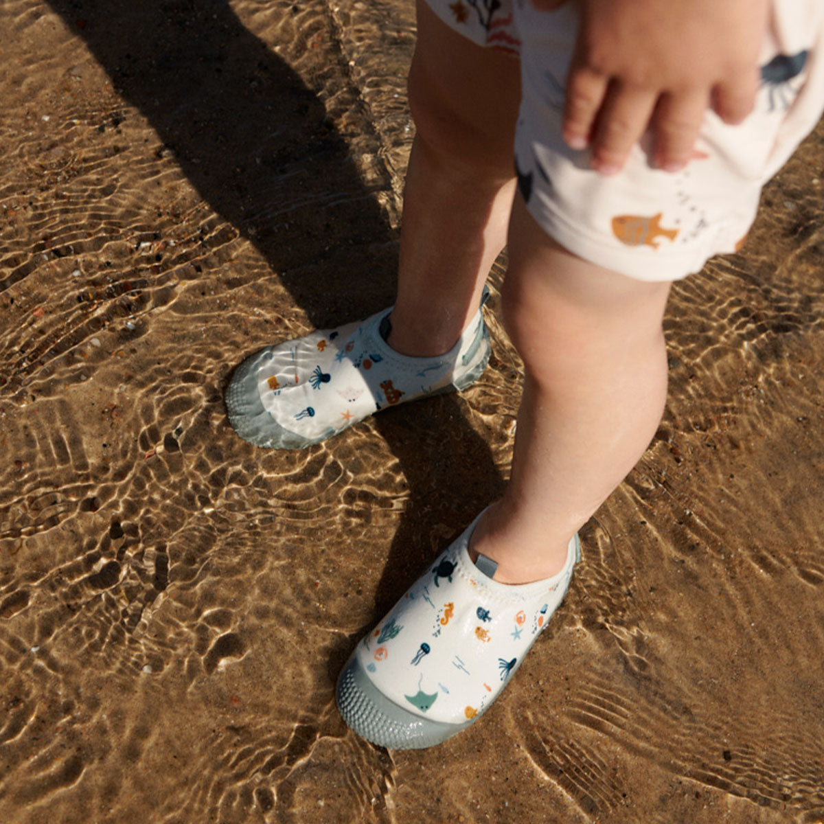 Zwemmen wordt dubbel zo leuk én veilig met de fijne sanjia flounce zwemschoenen in de variant sea creature/sandy van het merk Liewood. VanZus