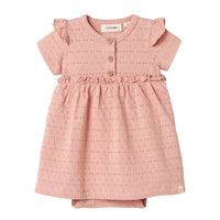 De baby jamla romperjurk in misty rose van het merk Lil' Atelier is een must-have voor de garderobe van jouw kleintje. Met een combinatie van 96% biologisch katoen en 4% elastaan biedt deze jurk zowel comfort als flexibiliteit, ideaal voor actieve pasgeborenen. VanZus
