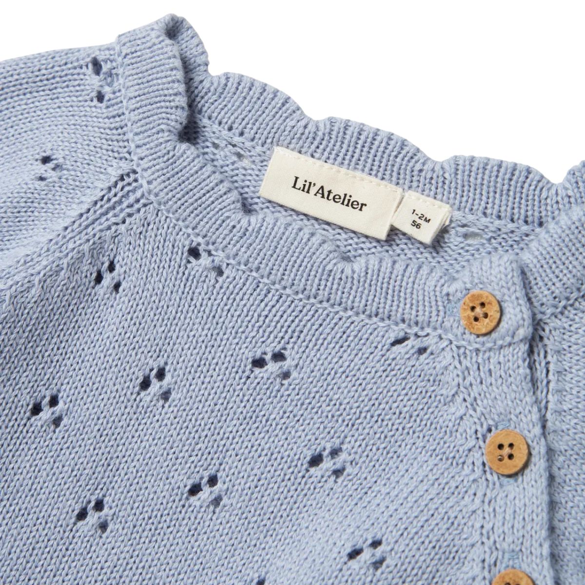 Lil' Atelier baby Jola knit shirt in zen blue is gemaakt van biologisch en gerecycled katoen. Comfortabele regular fit met O-hals en knoopsluiting. Met mooie schelp details. Hip en stijlvol! VanZus
