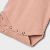 Dit comfortabele en schattige baby luna rompertje in de variant misty rose van het merk Lil' Atelier is echt de ultieme basic romper voor in de kledingkast van je kleintje! VanZus