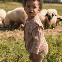 Het baby gebreid vestje in roebuck van Lil' Atelier is gemaakt van 100% RWS-gecertificeerde wol voor comfort en duurzaamheid. Met ruches, geribde zoom en knoopsluiting. Perfect voor herfst/winter. VanZus
