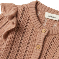Het baby gebreid vestje in roebuck van Lil' Atelier is gemaakt van 100% RWS-gecertificeerde wol voor comfort en duurzaamheid. Met ruches, geribde zoom en knoopsluiting. Perfect voor herfst/winter. VanZus