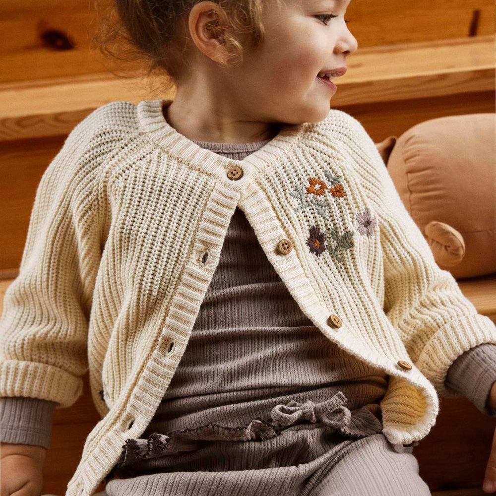 Maak de outfits van je kleintje net een beetje warmer met dit te leuke emlen longsleeve knit vest in de kleur birch van het merk Lil' Atelier. Dit vestje houdt je kindje lekker warm en ziet er ook nog eens superschattig uit! VanZus