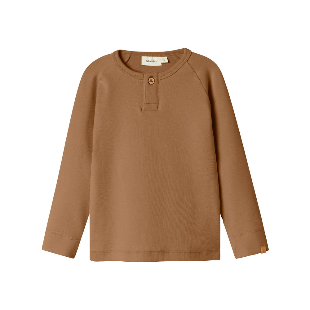 Het Lil' Atelier gayo slim shirt in de kleur sepia tint is een stijlvolle top die perfect is voor het creëren van een trendy outfit voor je kind. Dit shirt is gemaakt van 57% biologisch katoen, 38% TENCEL™ Lyocell en 5% elastaan, waardoor het niet alleen comfortabel, maar ook milieuvriendelijk is. VanZus