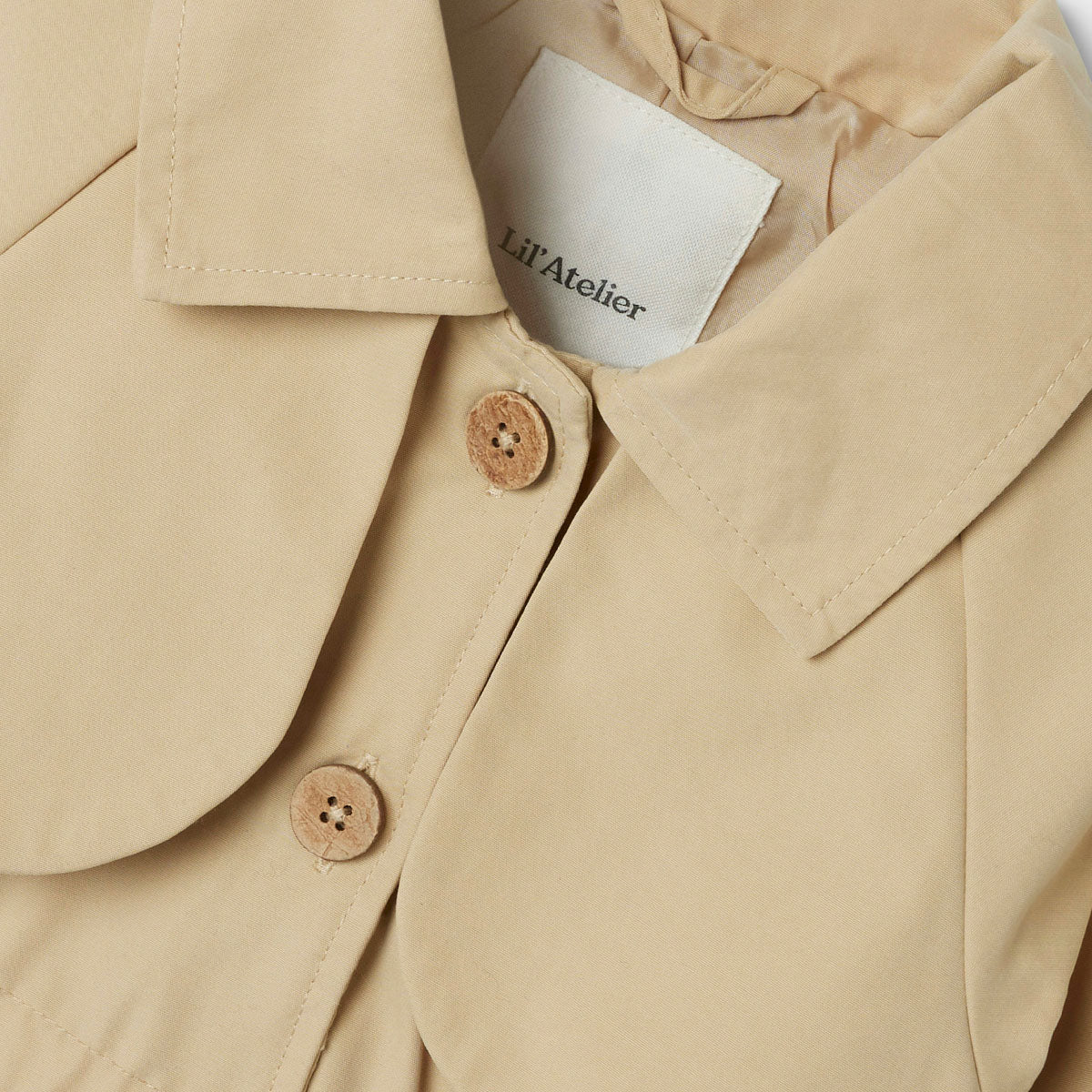 De madelin trenchcoat in de kleur irish cream van het merk Lil' Atelier is een absolute must have zomer. Deze stijlvolle zomerjas is gemaakt van gerecycled polyester en katoen, waardoor het niet alleen trendy is, maar ook duurzaam. VanZus