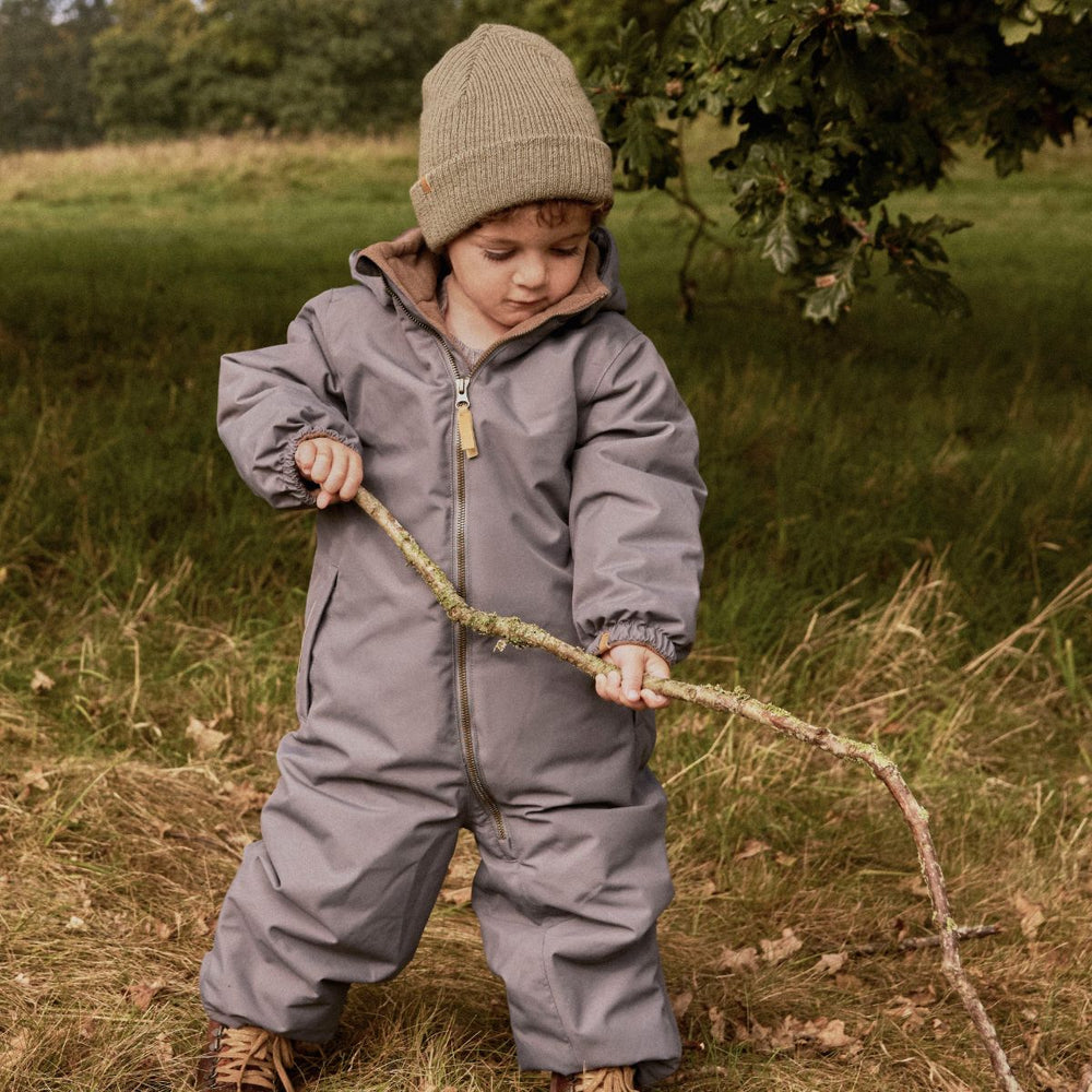 De Lil' Atelier nanson knit muts in de kleur overland trek is de perfecte finishing touch voor de winteroutfit van je kleintje. De muts is gemaakt van een zachte gebreide stof, namelijk 100% wol, en houdt het hoofdje lekker warm tijdens de koude dagen. VanZus