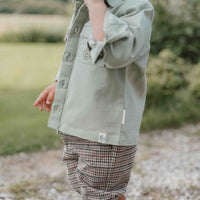 Wat een stoer overshirt in de kleur green van Little Dutch! Voor de kleine binken en avonturiers! Het overhemd heeft een klassieke kraag en een hout-look knoopsluiting. Twee borstzakjes, waarvan één versierd met een klein borduursel van een tractor maken de stoere look compleet. VanZus 