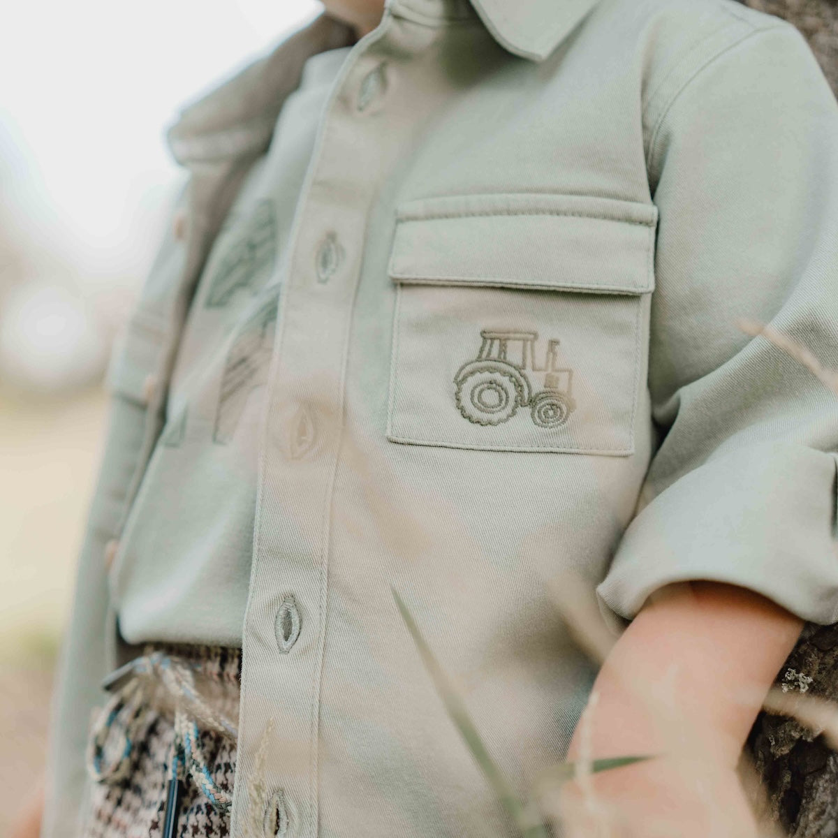 Wat een stoer overshirt in de kleur green van Little Dutch! Voor de kleine binken en avonturiers! Het overhemd heeft een klassieke kraag en een hout-look knoopsluiting. Twee borstzakjes, waarvan één versierd met een klein borduursel van een tractor maken de stoere look compleet. VanZus 