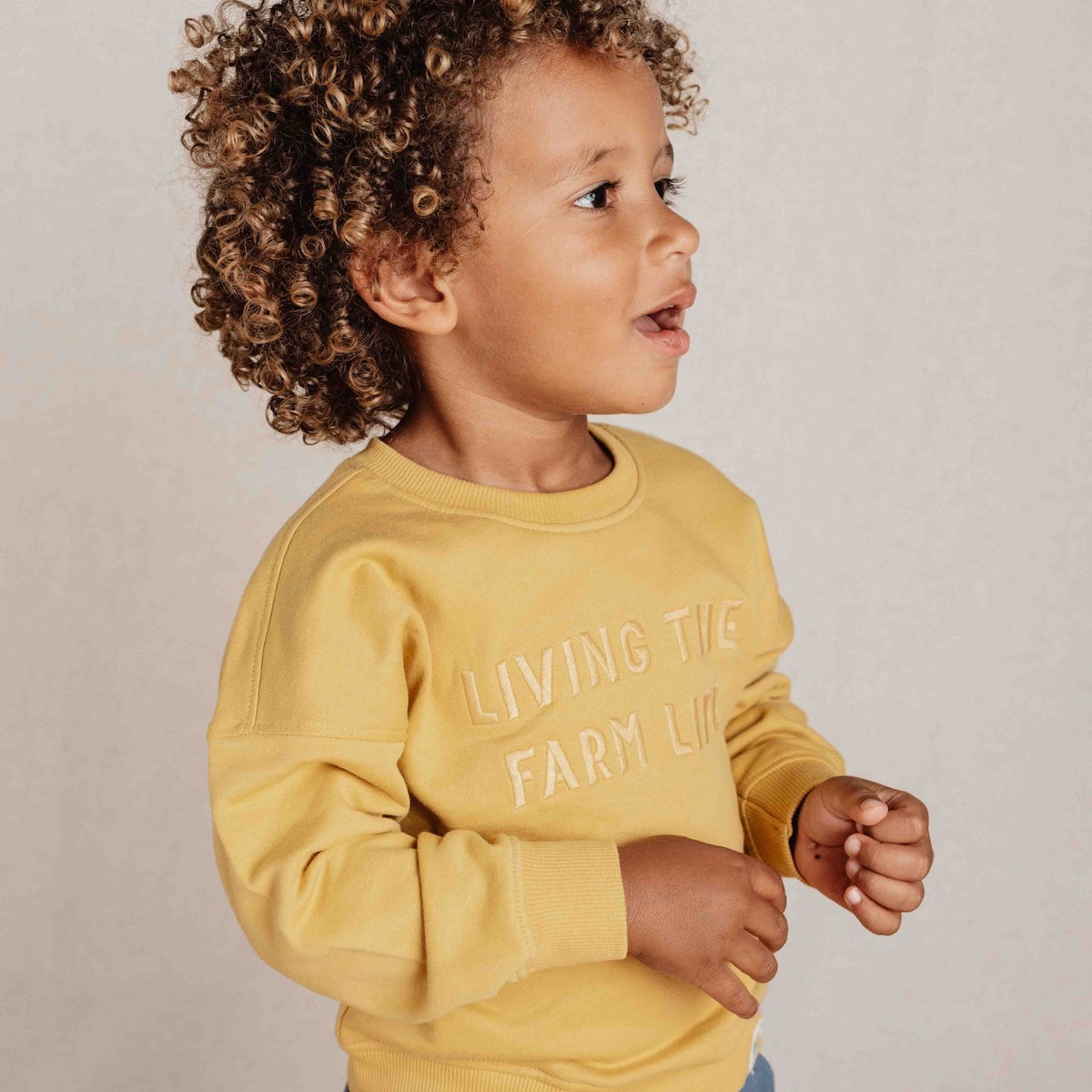 Deze sweater van Little Dutch in de kleur mustard yellow (geel) heeft vrolijke, geborduurde letters met de tekst "Living The Farm Life" op de voorzijde. Heerlijk zacht door het zachte biologisch katoen en daardoor is het sweatshirt heel comfortabel. VanZus