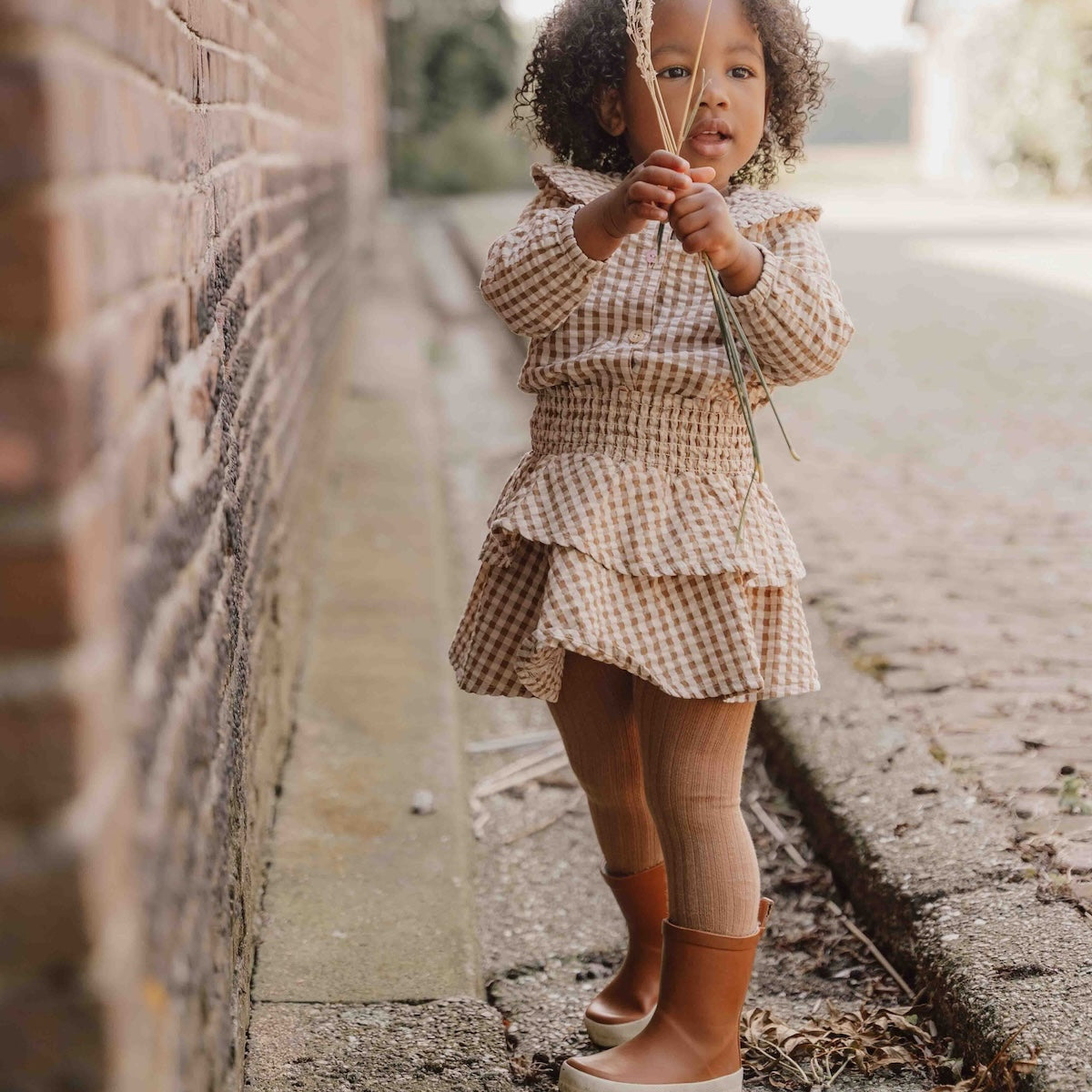 Hoe je de blouse brown check van Little Dutch ook combineert: je meisje zal er geweldig uitzien! De geruite blouse met lange mouwen heeft een bruin-wit patroon en een mooie opvallende kraag met ruches. Zo ziet de blouse er meteen heel bijzonder en meisjesachtig uit. De stof met textuur is van biologisch katoen. VanZus