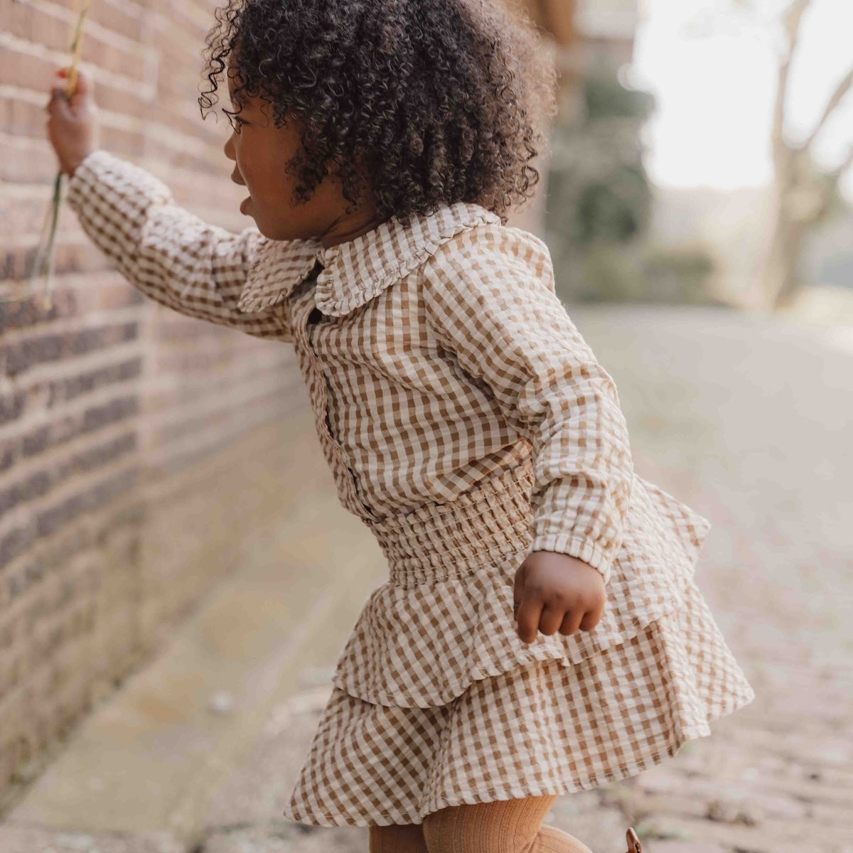 Hoe je de blouse brown check van Little Dutch ook combineert: je meisje zal er geweldig uitzien! De geruite blouse met lange mouwen heeft een bruin-wit patroon en een mooie opvallende kraag met ruches. Zo ziet de blouse er meteen heel bijzonder en meisjesachtig uit. De stof met textuur is van biologisch katoen. VanZus