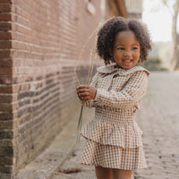 Hoe je de blouse brown check van Little Dutch ook combineert: je meisje zal er geweldig uitzien! De geruite blouse met lange mouwen heeft een bruin-wit patroon en een mooie opvallende kraag met ruches. Zo ziet de blouse er meteen heel bijzonder en meisjesachtig uit. De stof met textuur is van biologisch katoen. VanZus