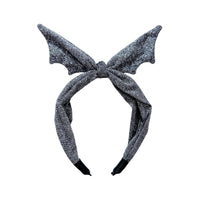 Een beetje griezelig, maar stijlvol, dat is de Rockahula shimmer bat diadeem met strik. Deze diadeem is de haaraccessoire voor Halloween. VanZus