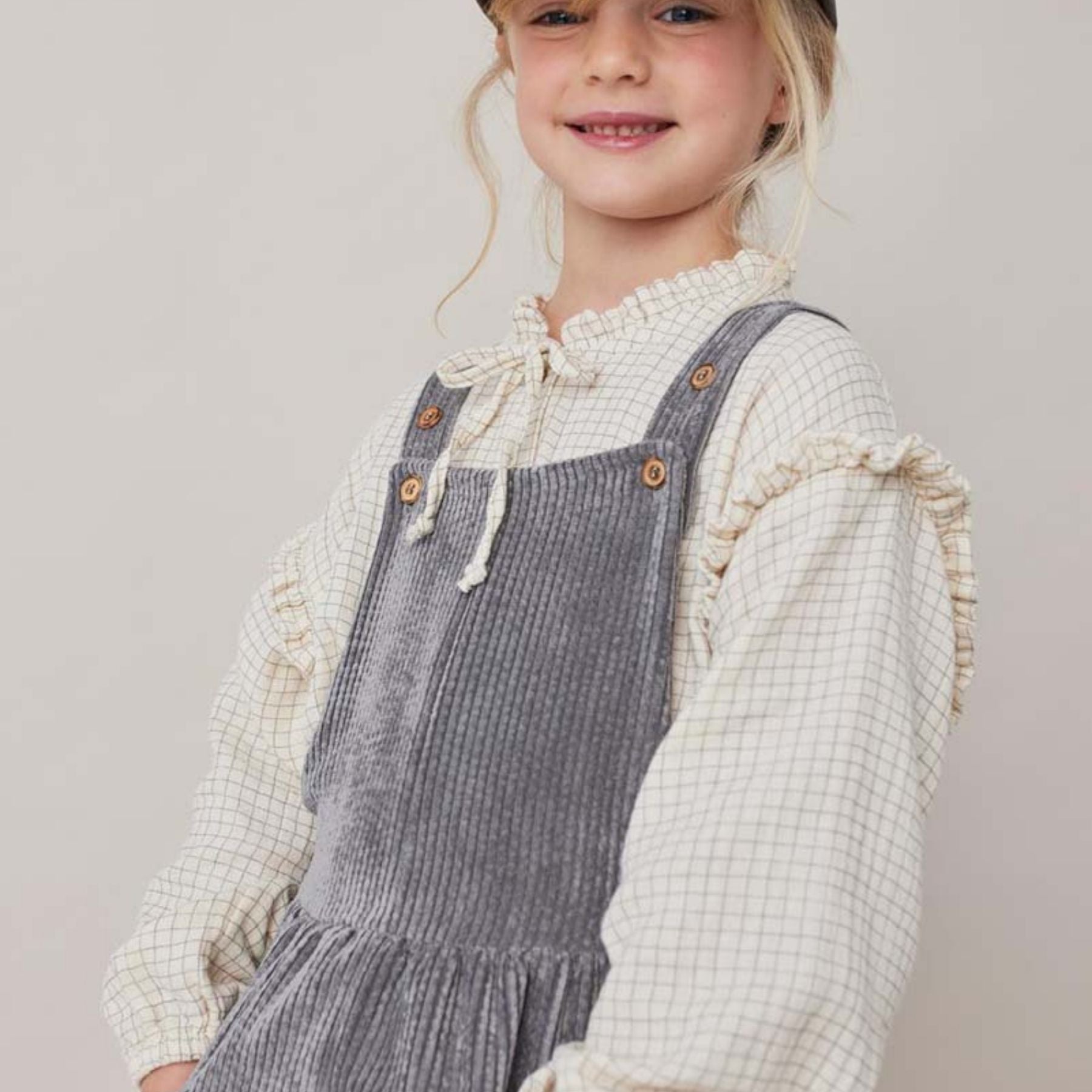 De blouse mini check crudo van Tocoto Vintage is een schattig, wit blouseje met subtiele ruitjesprint,  ruches, een strikje en houten knoopjes. In de maten 98-140. Combineer met een leuk broekje of rokje. VanZus