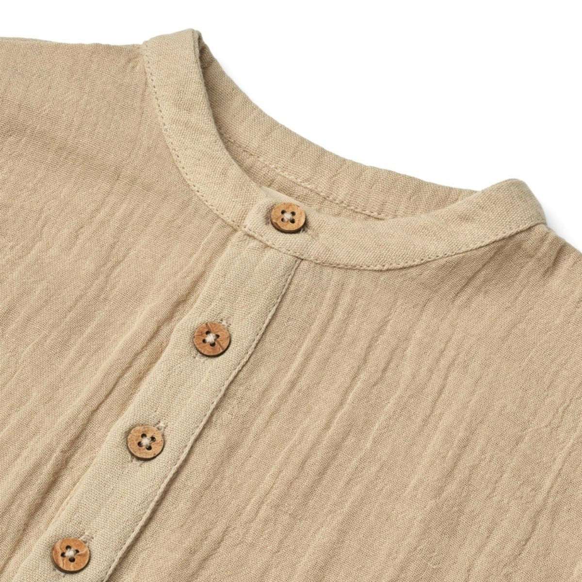 Svend shirt van het merk Wheat in de kleur soft sand: korte mouwen, knoopjes, loose fit, zandkleur en gemaakt van zacht en duurzaam materiaal. Combineer met bijpassende short voor een complete look. VanZus