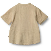 Svend shirt van het merk Wheat in de kleur soft sand: korte mouwen, knoopjes, loose fit, zandkleur en gemaakt van zacht en duurzaam materiaal. Combineer met bijpassende short voor een complete look. VanZus