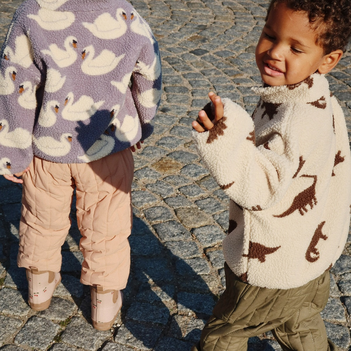 Houdt jouw kleintje van dino's? Dan is dit schattige jody teddy jasje van Konges Slojd in de print dino silhouette perfect! De teddyjas heeft een zachte teddy stof met een leuk printje van dino's. VanZus