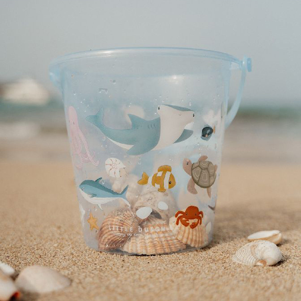 Maak een dagje strand nog leuker met dit blauwe transparante schelp emmertje van Little Dutch. De emmer is uitgevoerd met een super mooie waterdieren print. Door het transparante materiaal kan je alle vangsten goed bekijken. VanZus