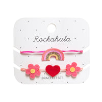 Armcandy voor jouw mini: Rockahula’s hippy rainbow armbandjes set. Een armbandje met regenboog in de kleuren roze, geel en goud en een armbandje met roze bloemen en nepleren rode hart. Eenvoudig verstelbaar. VanZus