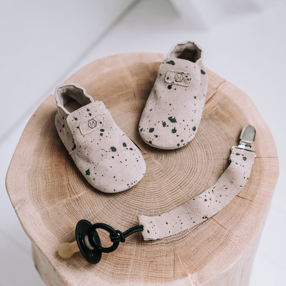 Op zoek naar stijlvolle eerste schoentjes? Dat zijn de Mavies first steps sand paint. Deze babyslofjes zijn van beige suède met zwarte spetters. De soepele zool zorgt voor goede afwikkeling van de voet. VanZus.